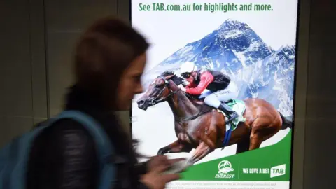 Getty Images A woman walks past a betting advertisement