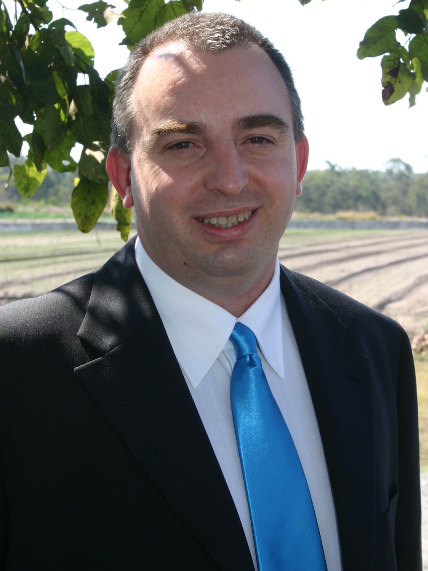 A man wearing a suit and tie, smiling.