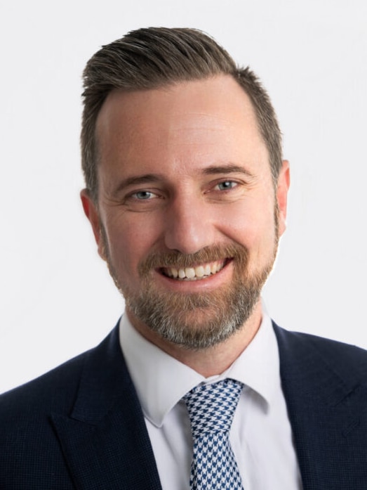 A man wearing a suit and tie, smiling.